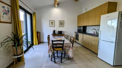 a kitchen with a table and a white refrigerator at Gîte le Micocoulier in Carpentras