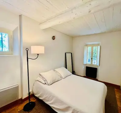 a bedroom with a white bed and a lamp at Villa climatisée avec piscine in Gordes