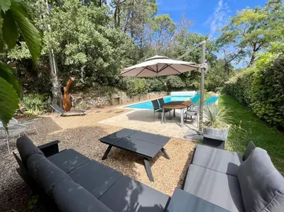 a patio with a couch and an umbrella next to a pool at Villa climatisée avec piscine in Gordes