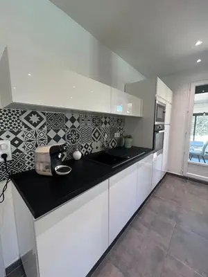 a kitchen with white cabinets and a black counter top at Villa confort avec piscine in Entraigues-sur-la-Sorgue