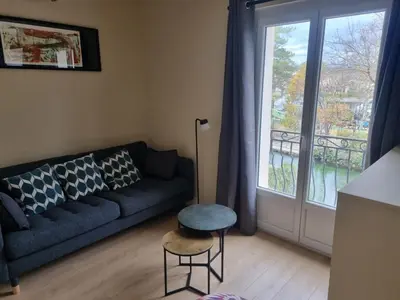 a living room with a blue couch and a window at La maison du quai in LʼIsle-sur-la-Sorgue