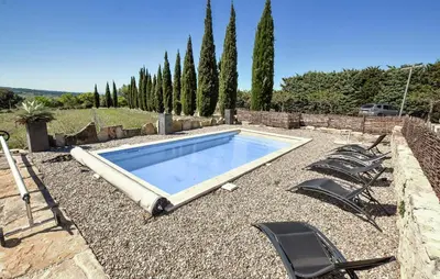 a swimming pool with chairs and a group of trees at Baumann 1 in Bédoin