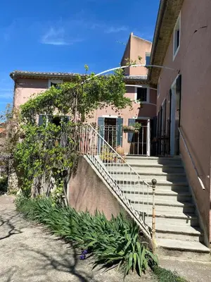 a building with a staircase leading to a house at La Maison Rose I Maison de village familiale in Lagnes