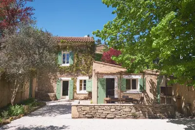 a stone house with a green door and a stone wall at Maison provençale avec jardin in Velleron