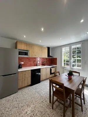 a kitchen with a wooden table and a refrigerator at Charmant appartement rénové, à 15 mn d'Avignon et de son festival in Entraigues-sur-la-Sorgue