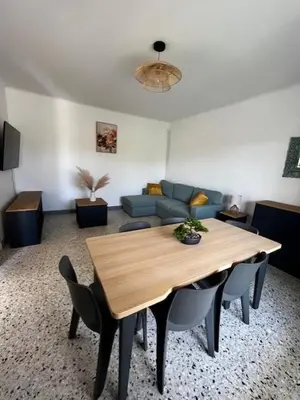 a living room with a wooden table and a couch at Charmant appartement rénové, à 15 mn d'Avignon et de son festival in Entraigues-sur-la-Sorgue