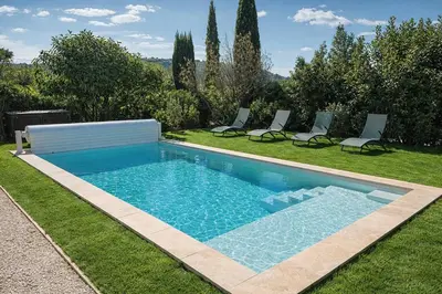 a swimming pool in a yard with two chairs at Maison en pierre avec piscine chauffée, jacuzzi et vue sur Gordes in Gordes