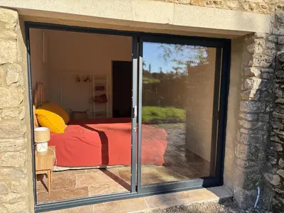 a sliding glass door leading to a bedroom with a bed at Maison en pierre avec piscine chauffée, jacuzzi et vue sur Gordes in Gordes