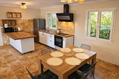 a kitchen with a wooden table with chairs and a dining room at Maison en pierre avec piscine chauffée, jacuzzi et vue sur Gordes in Gordes