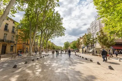 a street in a city with people walking and trees at Le Mirabeau - Hypercenter studio - Wifi - Train station in Aix-en-Provence