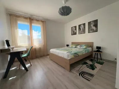 a bedroom with a white bed with pink flowers on it at Appartement Lumineux avec Balcon in Carpentras