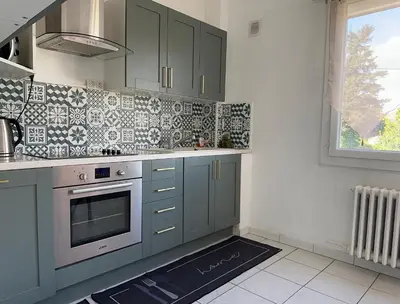 a kitchen with green cabinets and a red bed in it at Appartement Lumineux avec Balcon in Carpentras