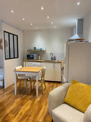 a living room with a table and a kitchen at Studio Cosy in Pélissanne