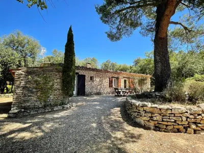 a stone house with a tree and a stone wall at Maison paisible au coeur du Luberon in Bonnieux