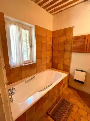 a large bath tub in a bathroom with a window at Maison paisible au coeur du Luberon in Bonnieux