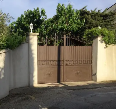 a fence with a wooden gate with a tree behind it at 1 chambre 1 cuisine & salle d'eau privées avec piscine et jacuzzi in Eyragues