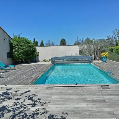 a swimming pool with a bench on a wooden deck at 1 chambre 1 cuisine & salle d'eau privées avec piscine et jacuzzi in Eyragues