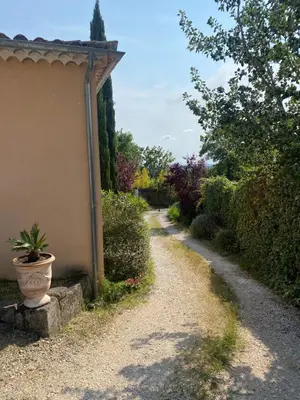 a gravel road next to a house with a potted plant at Le gîte de Cambuisson in Velleron