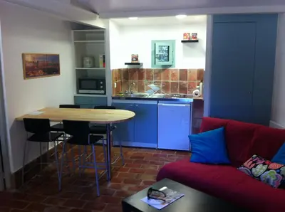 a living room with a couch and a table and a kitchen at Maisonnette dans un parc du 18ème in Aix-en-Provence