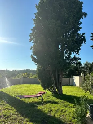 a park bench sitting in the grass next to a tree at Brin d'Olivier en Luberon in Gargas