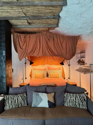 a bed with a canopy above a couch at CaBaNa 52 La Suite troglodyte Proche Lourmarin in Cadenet