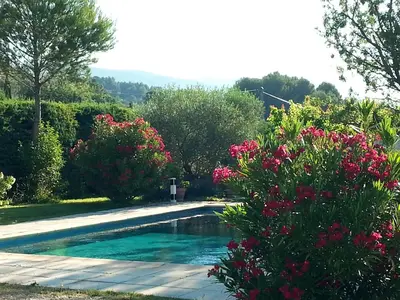 a swimming pool in a garden with pink flowers at Maison de charme en Luberon à proximité de Lourmarin piscine privée et grand jardin in Puyvert