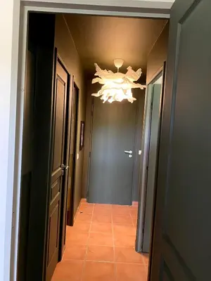 a hallway with a chandelier on the ceiling and a hallway with a door at Élégant appartement sur le Golf de Pont Royal in Mallemort