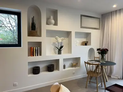 a living room with shelves and a table at La Réserve Hôtes in Aix-en-Provence