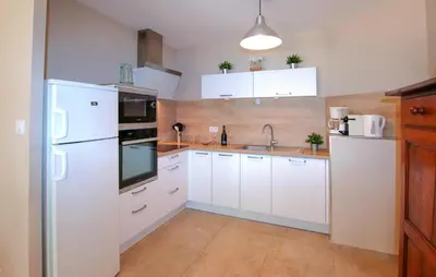 a kitchen with white cabinets and a white refrigerator at Charmant Mazet Provençal in Mazan
