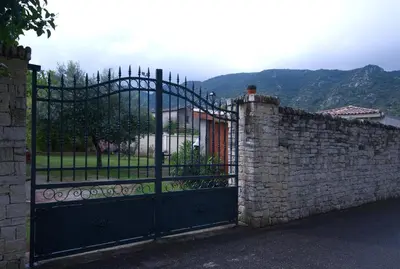 a black gate with a stone wall with a stone fence at Catherine&Martial in Maubec