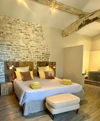 a bedroom with a large bed with a stone wall at Le Mas de Cabrières in Cabrières-dʼAvignon