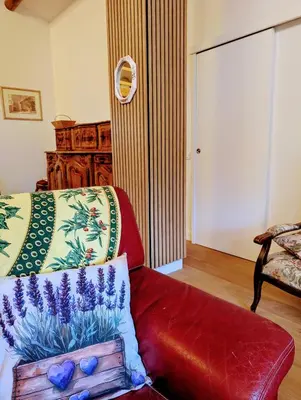 a living room with a red couch and a bed at La poumo d'amour in La Tour-dʼAigues