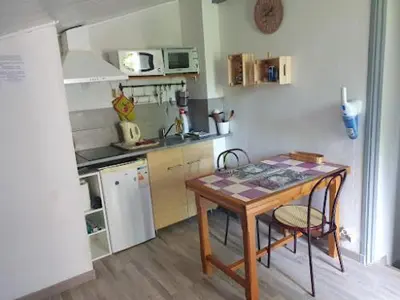 a kitchen with a wooden table and a table and chairs at Les Marronniers Charmant petit appartement a La Tour d'Aigues Vaucluse in La Tour-dʼAigues