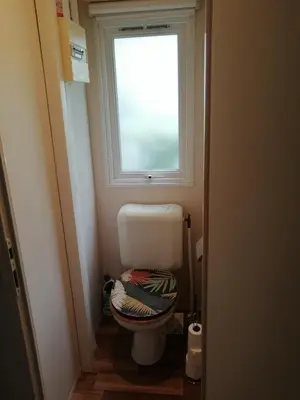 a small bathroom with a toilet with a window at mobil home chez ANIK & ALAIN in La Roque-dʼAnthéron