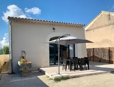 a table and chairs under an umbrella on a patio at Maison rénovée 3 chambres in Mollégès