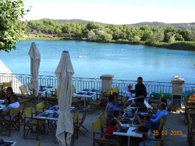 a group of people sitting at tables by a lake at Appartement neuf avec vue in Mallemort