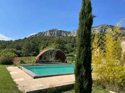 a pool in a garden with a mountain in the background at Une maison en Provence piscine au pied du Luberon in Mérindol