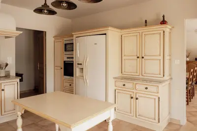 a kitchen with a table and a refrigerator at La Villa Des Garrigues in Mazan