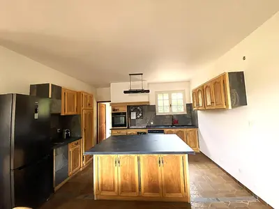 a kitchen with wooden cabinets and a black refrigerator at Les Mourguettes maison familiale avec piscine et garage sur 2000 m2 de terrain en campagne in Carpentras