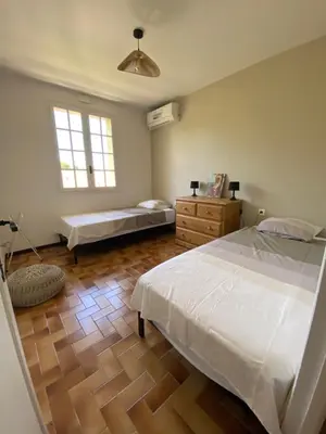 a bedroom with two beds and a wooden floor at Les Mourguettes maison familiale avec piscine et garage sur 2000 m2 de terrain en campagne in Carpentras