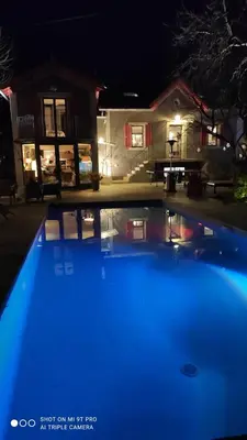 a blue swimming pool in front of a house at night at Maison de charme à Aix-en-Provence in Aix-en-Provence
