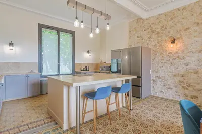 a kitchen with a large island with two blue bar stools at Le Champ des Cigales in Noves