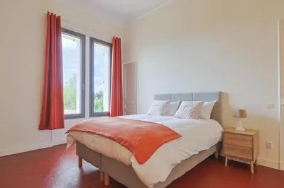 a bedroom with a large bed with red curtains at Le Champ des Cigales in Noves