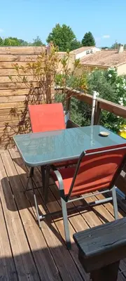 a table and a chair on a deck at Nid douillet au cœur du Vaucluse in Entraigues-sur-la-Sorgue