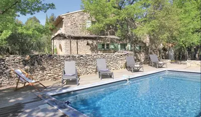 a swimming pool with chairs and a stone wall at Authentique Bergerie Coeur Luberon in Lacoste