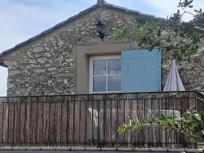 a house with a fence and a window and an umbrella at Petit gîte et Grande piscine in Blauvac