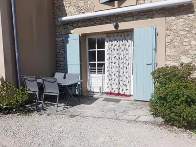 a table and chairs in front of a building with a door at Petit gîte et Grande piscine in Blauvac
