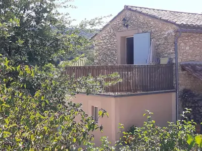a house with a balcony with an umbrella on it at Petit gîte et Grande piscine in Blauvac