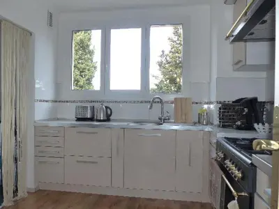 a white kitchen with a sink and two windows at Agréable appartement Montfavet Avignon in Avignon