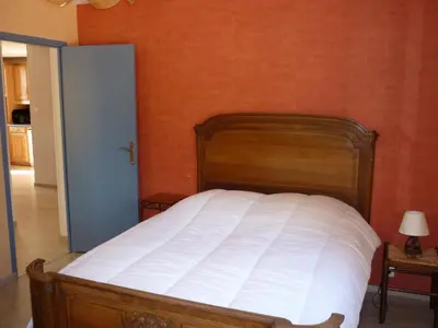 a bed in a bedroom with an orange wall at Gite PROVENCE MONT VENTOUX in Malemort-du-Comtat